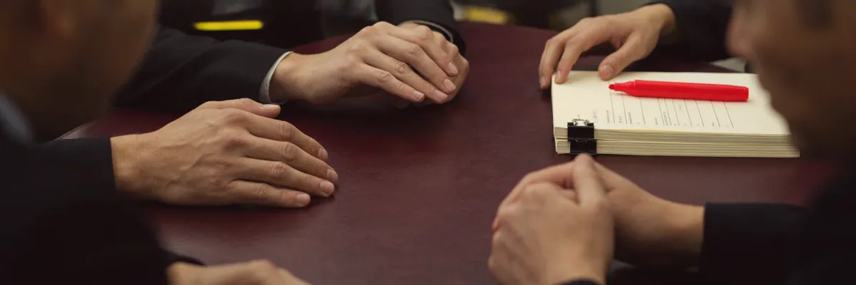 Two colleagues reviewing a small stack of blank pages fastened with a binder clip, a red highlighter beside them.