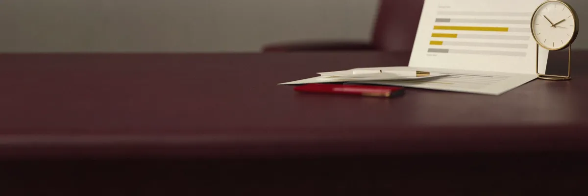 A printed report showing a bar-chart graphic beside a modern desk clock and a pen.