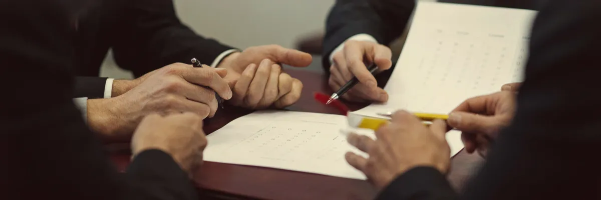 Two colleagues reviewing a printed scorecard with a dot-rating grid, marking it with a pen.